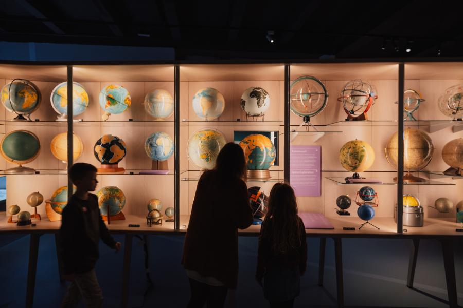 Een gezin kijkt naar de globes in MAP - Mercator
