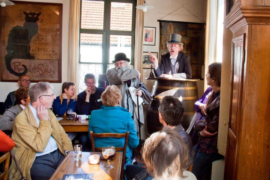 Een man vertelt verhalen vanuit de sprekerston in de herberg van het Volkskundemuseum