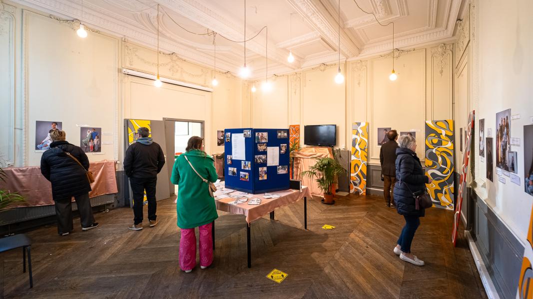 Een vijftal mensen bekijkt een tentoonstelling met foto's en tekstpanelen aan de muren