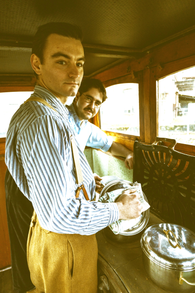 Twee reenactors staan in de stuurhut van spits Alyv. Ze koken.